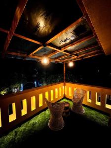 a patio with two chairs and a roof at night at The Orchard House in Raichak
