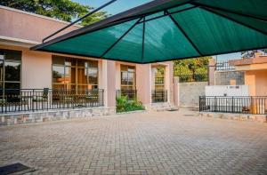 un grand parapluie vert devant un bâtiment dans l'établissement Studio - Sleeps 2 - Free Shuttle, à Entebbe