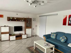 ein Wohnzimmer mit einem blauen Sofa und einem TV in der Unterkunft Ferienwohnung Tina in Nettersheim