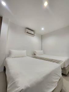 two beds in a room with white walls at Rock Valley Private Pool Villa 3 Bedroom Phuket town in Ban Bang Khu