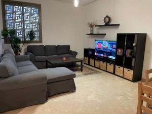 een woonkamer met een bank en een flatscreen-tv bij Appartement a la marina de salé in Sale