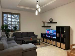 a living room with a couch and a flat screen tv at Appartement a la marina de salé in Sale