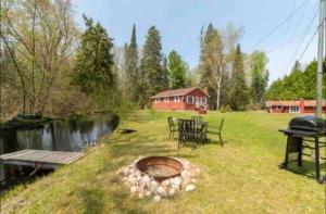 a campsite with a grill and a picnic table next to a river at Mud Creek Cottage in Cheboygan