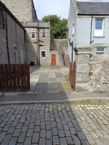 a cobblestone street in an alley with houses and a orange door at Stylish one bed flat with private parking in Aberdeen