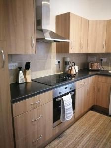 a kitchen with wooden cabinets and a stove top oven at Stylish one bed flat with private parking in Aberdeen