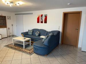ein Wohnzimmer mit einem blauen Sofa und einem Tisch in der Unterkunft Ferienwohnung Tina in Nettersheim