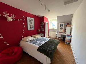 um quarto com uma parede vermelha, uma cama e uma secretária. em Maison 80è anniversaire D-Day em Le Manoir