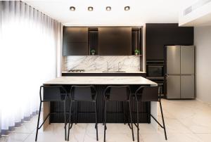 une cuisine avec des placards noirs et un comptoir avec des tabourets dans l'établissement 4Corners Retreat- Center of Town, Jerusalem, à Jérusalem