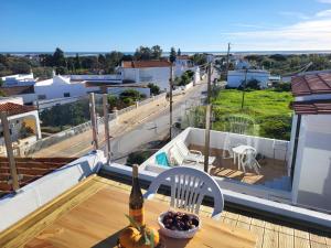 una mesa con una botella de vino y un bol de fruta en el balcón en Casas Algarvias en Arroteia de Baixo