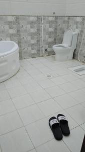 a pair of slippers on a bathroom floor with a toilet at Traveler Rooms 2 in Al Madinah