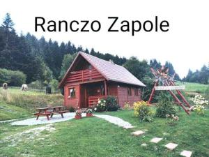 mały domek z bali ze stołem piknikowym i ławką w obiekcie Ranczo Zapole w mieście Zasadne