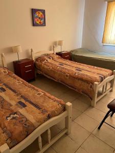 a room with two beds and two tables with lamps at Casa Rufino Ortega in Mendoza