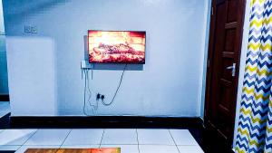 een tv op een witte muur in een kamer bij One Bedroom at Bamburi in Mombasa