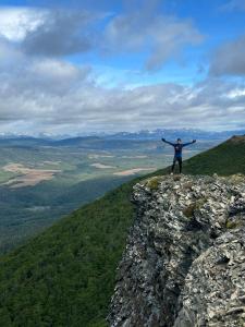 une personne debout au sommet d'une montagne, les bras sortis dans l'établissement Apartamento Vista al Estrecho, à Punta Arenas