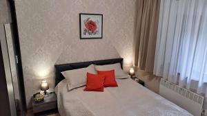 1 dormitorio con 1 cama con 2 almohadas rojas en Lusi Holiday, Смолянски езера, en Smolyan