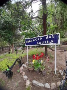 un cartel azul y blanco en un parque con flores en Complejo de Cabañas Estancia Del Águila en Mina Clavero