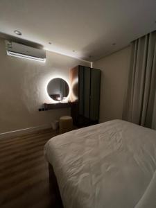 een slaapkamer met een wit bed en een spiegel bij شقة فاخرة بالقرب من البوليفارد Apartment next to boulevard city- world &arean kingdom in Riyad