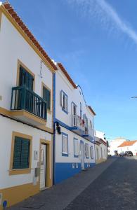 a row of blue and white buildings on a street at CASA DIAS RAPOSO by Stay in Alentejo in Vila Nova de Milfontes