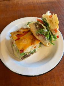 un plato blanco con un sándwich y una ensalada en Sítio CRIA - Hospedagem Sustentável & Experiências Rurais, en Três Coroas