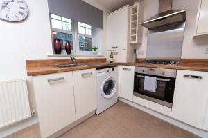 a kitchen with white cabinets and a washer and dryer at Pacific House in Thornaby on Tees