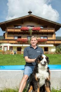 a man sitting next to a dog in front of a house at Landhaus Aubauerngut in Radstadt