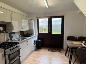 a kitchen with a stove and a table and a door at Above the harbour wick in Wick