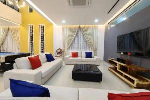 ein Wohnzimmer mit einem weißen Sofa und einem Fernseher in der Unterkunft TropINN Villa- CornerHouse•BIGPool•BBQ•KTV•Billard in Bandar Penawar