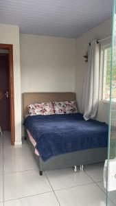 - une chambre avec un lit doté de draps bleus et une fenêtre dans l'établissement Casa praia da Gamboa garopaba, à Garopaba