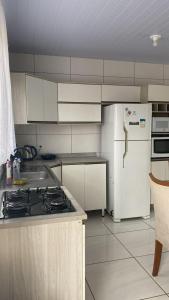 La cuisine est équipée de placards blancs et d'un réfrigérateur blanc. dans l'établissement Casa praia da Gamboa garopaba, à Garopaba