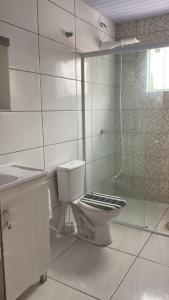 a white bathroom with a toilet and a shower at Casa praia da Gamboa garopaba in Garopaba