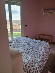 um quarto com uma cama e uma grande janela em Villa Cocuzza em Piozzo