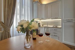 dos copas de vino y un jarrón de flores en una mesa en Art Apartment Luxury Tintori Suite, en Florencia