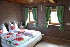 ハイリゲンブルートにあるFerienhaus Gompitzerのベッドルーム1室(緑のカーテン付きのベッド2台付)