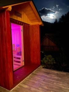 Casa de madera pequeña con puerta de color rosa en Alpine Wooden Villa with a View, en Gozd Martuljek