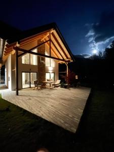 una casa con una gran terraza de madera por la noche en Alpine Wooden Villa with a View, en Gozd Martuljek