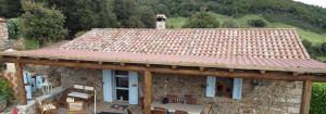 a stone house with a roof with a table and chairs at Stazzo Casa Bianco Fly in Aggius