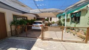 a fence in front of a house with a car at Garden Oasis Cottage in Windhoek