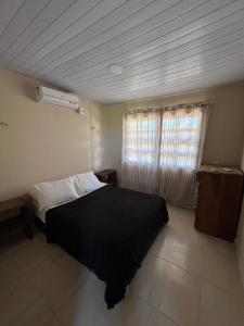ein Schlafzimmer mit einem schwarzen Bett und einem Fenster in der Unterkunft Casa do alto pipa in Pipa