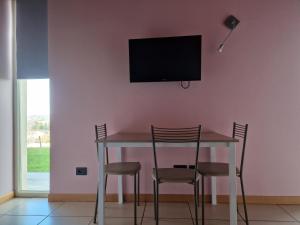 a dining room table with chairs and a television on a wall at Villa Cocuzza in Piozzo