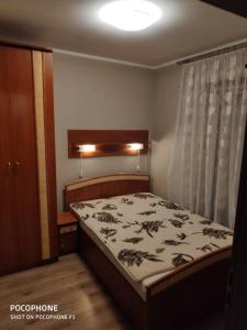 een kleine slaapkamer met een bed en een gordijn bij Apartament Podmiejska in Jastrzębie Zdrój