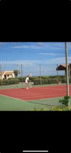 eine Person spielt Tennis auf einem Tennisplatz in der Unterkunft T2 village naturiste Aphrodite in Leucate