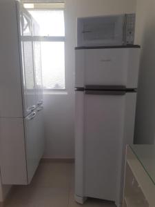 uma cozinha branca com um micro-ondas em cima de um frigorífico em Apartamento em Ondina - Jardim Apipema em Salvador