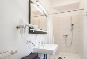 y baño blanco con lavabo y ducha. en Exclusive 2-room souterrain apartment, en Núremberg