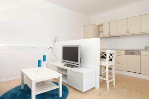 Una cocina blanca con escritorio y TV. en Exclusive 2-room souterrain apartment, en Núremberg