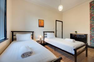 two beds in a room with white walls at Newcastle CITY Apartments,4 BEDROOM HOUSE,FREE STREET PARKING,8 SINGLE BEDS,FULL KITCHEN,ALL ROOMS WITH TVs,NETFLIX in Newcastle upon Tyne