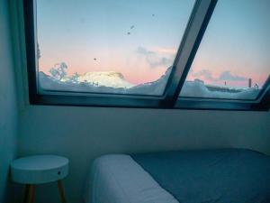 a window in a room with a bed and a stool at Aurora View Lapland, Sky View Bedroom in Kilpisjärvi