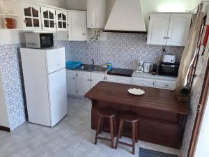 cocina con mesa de madera y nevera blanca en Casas Algarvias en Arroteia de Baixo