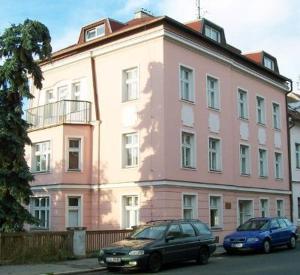 zwei Autos, die vor einem rosa Gebäude geparkt sind in der Unterkunft Almond in Teplice