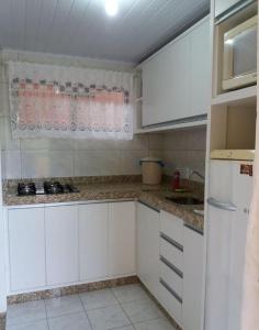 cocina con armarios blancos y encimera en Residencial Vista Bela, en Bombinhas