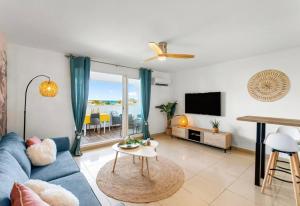 ein Wohnzimmer mit einem blauen Sofa und einem TV in der Unterkunft La Créola New! Grand Case - vue mer - appart 4p - King size in Grand Case